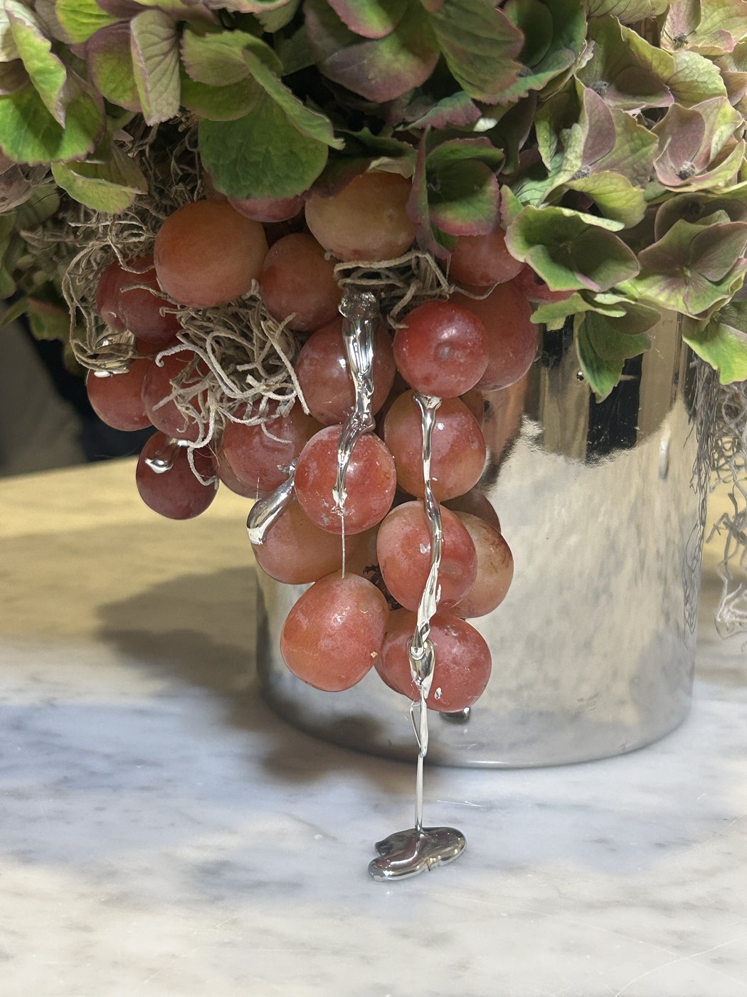 Silver drips running from grapes down to a small pool on the marble (photo 4 of 4)